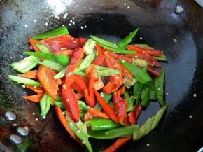 热锅下青红椒炒，直到青红椒变塌稍微变软时盛起。（如果不喜欢吃软的椒，喜欢吃脆硬的椒，则这步可以省略，青红椒在后续下肉片后下蒜苗前放入。）