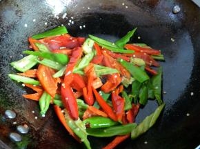 热锅下青红椒炒，直到青红椒变塌稍微变软时盛起。（如果不喜欢吃软的椒，喜欢吃脆硬的椒，则这步可以省略，青红椒在后续下肉片后下蒜苗前放入。）