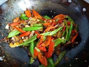 将肉片倒入翻炒几下，随后倒入青红椒一起翻炒均匀。