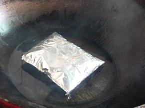 炒锅中放些许油，小火烧至冒烟（筷子插进去会立即冒出许多小气泡时），将鸡翅包放入烤。2分半钟后翻面继续再烤2分半钟（翻面时要快，否则容易油爆伤到）。过程中锡纸有膨胀是正常现象。