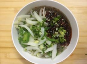 将煮好的红薯粉和配菜盛入碗中，倒入调好的料汁，撒上葱段，