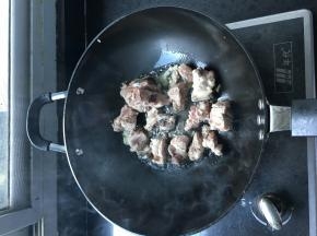 炒锅上火，放姜块、葱丝、蒜、将排骨爆炒，待排骨颜色由红变白，