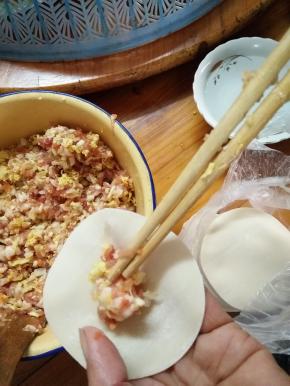 将胡萝卜，娃娃菜放入肉沫中搅拌，加适量的盐、料酒、酱油调味，然后开始包饺子如图