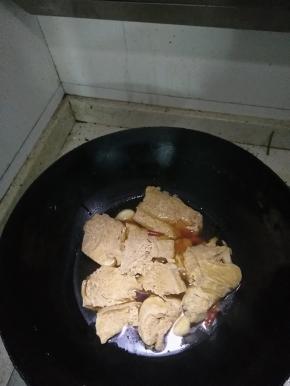 在锅内倒入适量的水，倒入在冷冻室冰过的白豆腐干，放入辣椒、大蒜、料酒