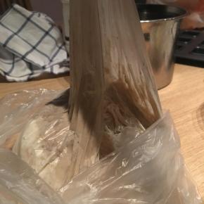 将保鲜袋袋口收紧，让里面的固体和液体混合，呈现出黏糊糊的状态就可以了，空气要挤出，但袋口收口时要注意给面团留出可以发酵一倍的空间，