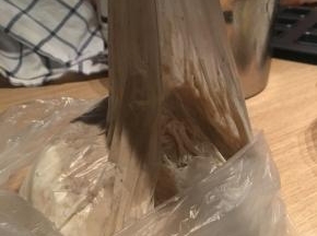 将保鲜袋袋口收紧，让里面的固体和液体混合，呈现出黏糊糊的状态就可以了，空气要挤出，但袋口收口时要注意给面团留出可以发酵一倍的空间，