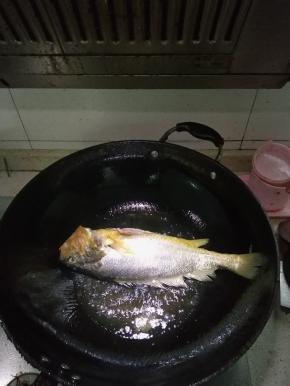 将黄鱼洗净，解剖好，在锅内倒入适量的花生油，放入盐，轻轻放入黄鱼