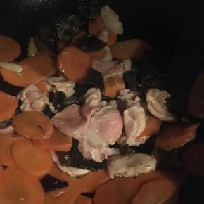 待胡萝卜炒制熟软后，加入肉片翻炒