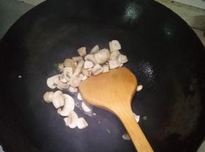 在锅内倒入适量的花生油，倒入切片的蘑菇，加少许盐翻炒