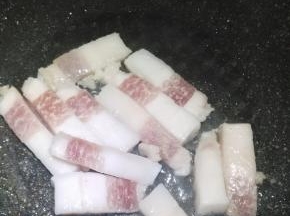 在锅内倒入适量的花生油，将肥肉放入锅里熬油