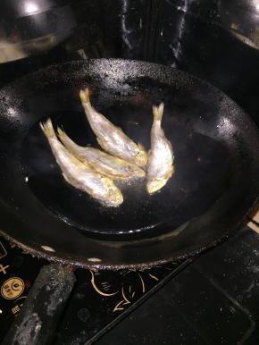 然后一条一条下入咸鱼，大火烧热后转小火慢慢煎。