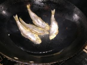 然后一条一条下入咸鱼，大火烧热后转小火慢慢煎。