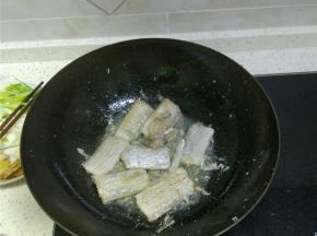 锅内放油，加热开小火，放入处理好的带鱼段，煎至两面微黄