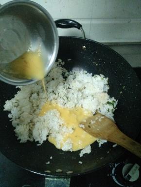 米饭炒散后调中火，将鸡蛋液倒入锅中，加入盐巴和鸡精。然后继续开大火翻炒，炒到鸡蛋液均匀凝固在米饭上。