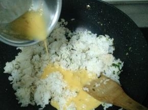 米饭炒散后调中火，将鸡蛋液倒入锅中，加入盐巴和鸡精。然后继续开大火翻炒，炒到鸡蛋液均匀凝固在米饭上。