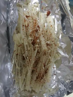 将炒好的肉末和汤汁一并浇在金针菇上，包好放入烤箱