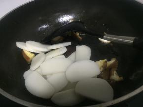 把年糕切片，也可以直接买片状年糕，待香菇变软后，加入年糕片，翻炒1-2分钟
