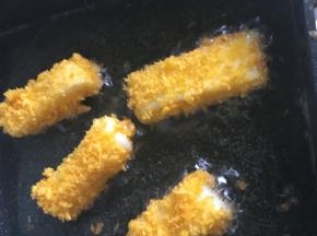 将滚好面包糠的奶糕条如油锅小火煎炸一会儿