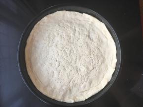 把发酵好的面团取出再揉下排气15分钟，用手压入披萨盘中边缘留厚些，用叉子撮几个排气小孔，