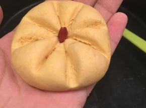 取一小团南瓜面团，用牙签或塑料刮刀，压出南瓜的条纹，中间加一粒枸杞做南瓜饼