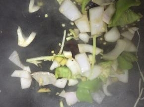 倒入洋葱和青椒，翻炒1-2分钟，至变软，再加入少量盐