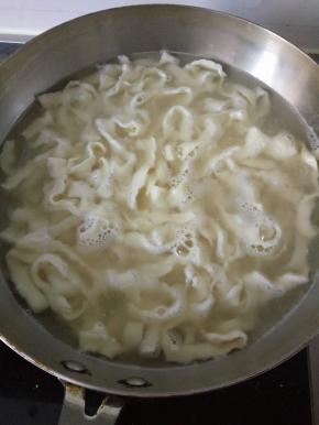 炒锅内烧水 将手擀面煮熟盛出在将面条过下凉水