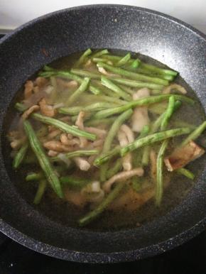 再加入洗好豆角加入锅内，翻炒豆角至青绿色加入水末过豆角大火等到水开。