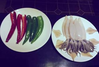 一斤鱿鱼，洗干净，去皮，头和触角分开；青红椒去籽洗净，姜蒜、洋葱适量切成末