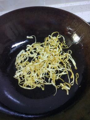 锅内放油烧热，爆香葱姜蒜，加入豆皮翻炒