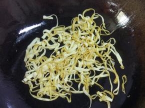 锅内放油烧热，爆香葱姜蒜，加入豆皮翻炒