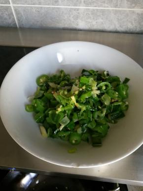 锅热后向锅内放入少许食用油，放入大蒜叶和尖椒，炒熟后盛盘