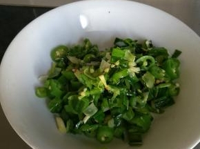 锅热后向锅内放入少许食用油，放入大蒜叶和尖椒，炒熟后盛盘