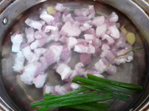 五花肉洗净切块，姜切几片、葱一部分切段，放入冷水锅中大火煮开焯水