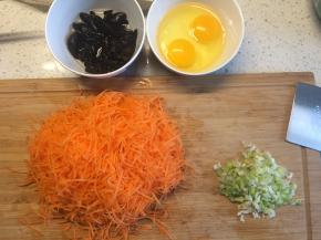 胡萝卜去皮擦成丝，木耳泡发，鸡蛋加盐打散，葱切葱花备用。