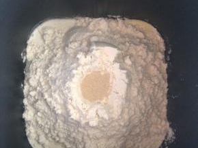 将中种所需要的材料放入面包机，先放液体类材料，然后是糖和面粉，最后在面粉中间挖一个小坑放上酵母，启动一次和面程序。