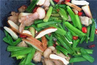 6、放入大蒜叶、香干一起爆炒，放入黄酒、盐