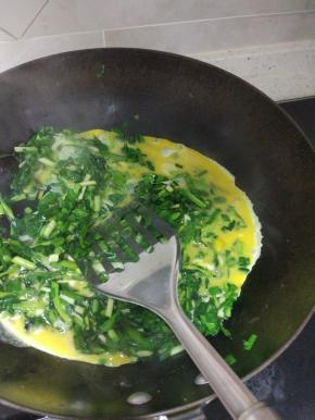 锅内放油烧热，加入韭菜，放入适量的盐，韭菜炒软倒入蛋液