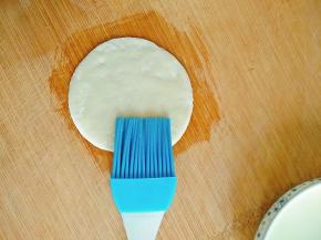 先刷一点油在案板上，防止粘连，然后取下一片饺子皮，在表面刷一层薄薄的油