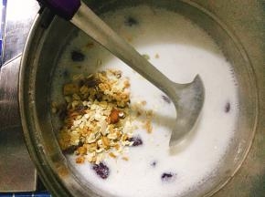待牛奶煮开后将麦片倒入锅中搅拌均匀。