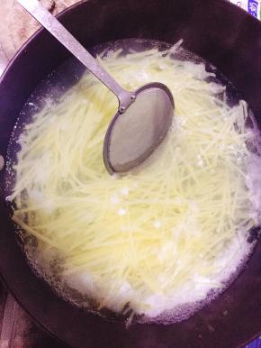 土豆擦丝入热水锅内焯熟。
