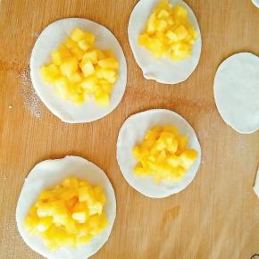 7.取饺子皮平铺于面板上，放上苹果馅，注意不要放太多，不然会包不住。