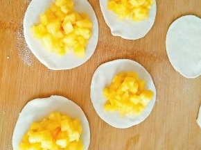 7.取饺子皮平铺于面板上，放上苹果馅，注意不要放太多，不然会包不住。