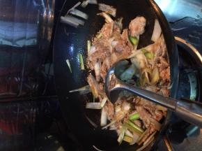 把葱放入锅中翻炒两分钟左右，放入羊肉翻炒