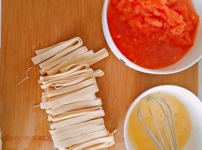 2．西红柿去皮切碎，鸡蛋加水打散，豆皮切丝。