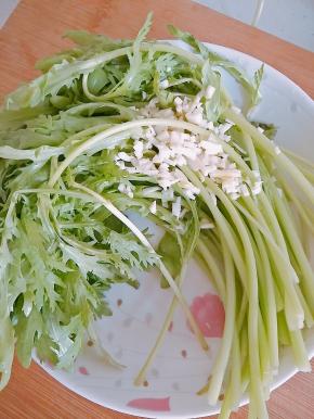 2．茼蒿洗好放入盘中，蒜切末放入茼蒿之上。