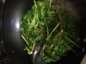 把茼蒿放入锅中翻炒几分钟，随后加入粉条翻炒