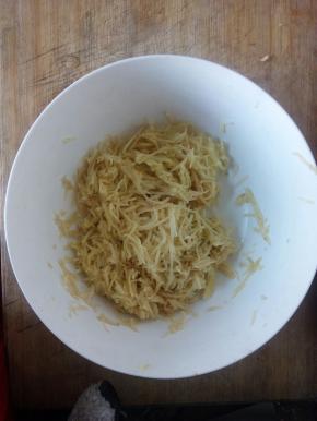 用刨丝器刨成土豆丝，不洗了，加入少许盐和鸡精，均匀搅拌，加入适量面粉。