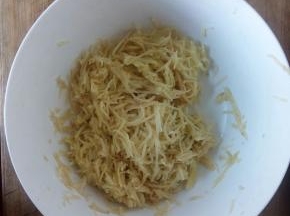 用刨丝器刨成土豆丝，不洗了，加入少许盐和鸡精，均匀搅拌，加入适量面粉。