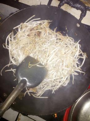 把豆芽放锅里炒。同时下辅料，爆炒十多分钟。