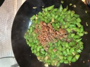 将肉馅倒入锅中，加少量的水煮一会儿，让豆角充分煮熟。